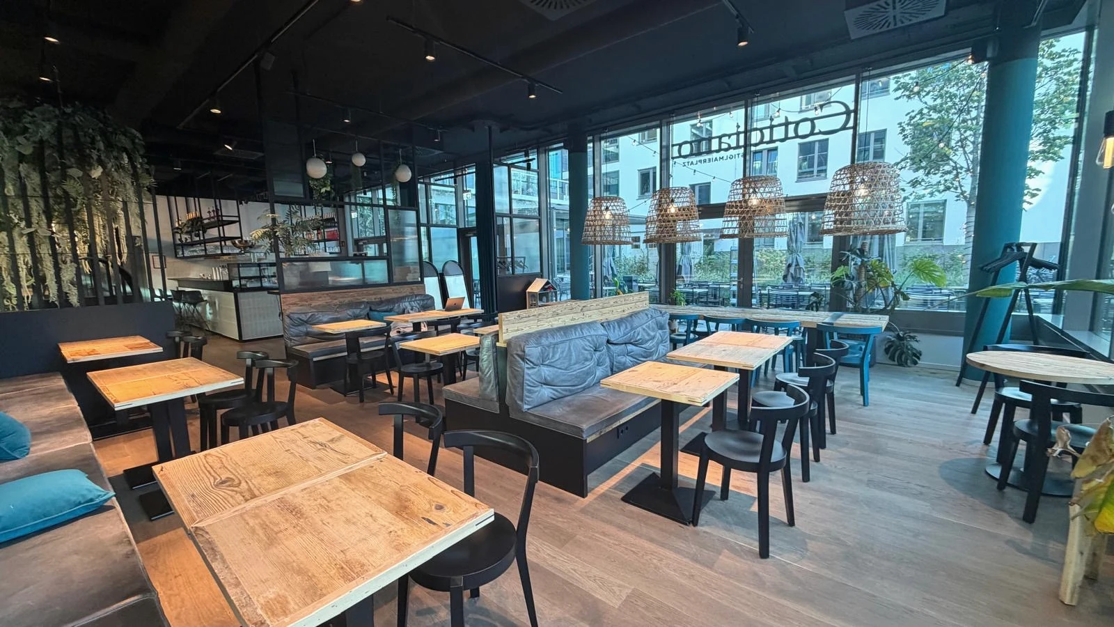 Convivio Restaurant in München: heller Gastraum mit Holztischen, Sitzbänken und Pendelleuchten